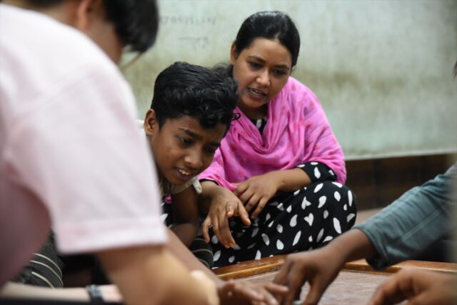 子どもたちのボードゲームの様子を楽しそうに見守る